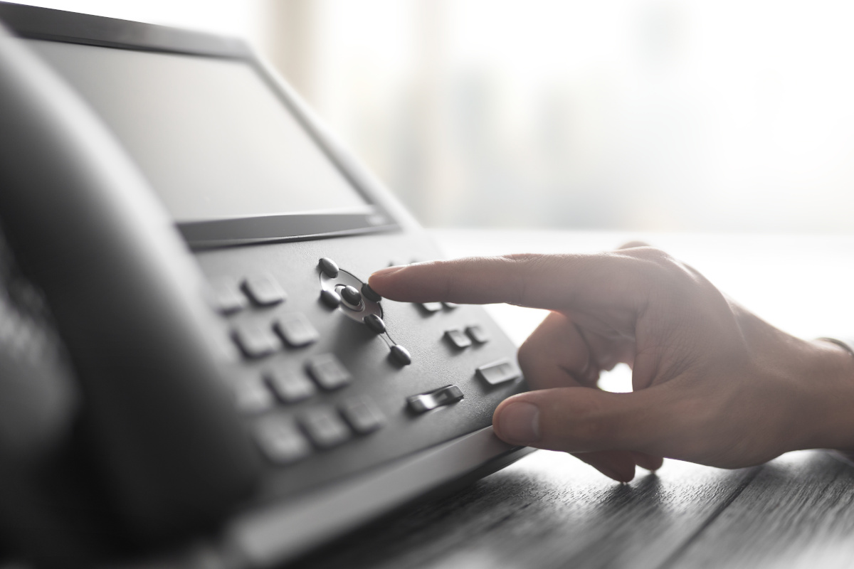 A hand pressing numbers on a business phone