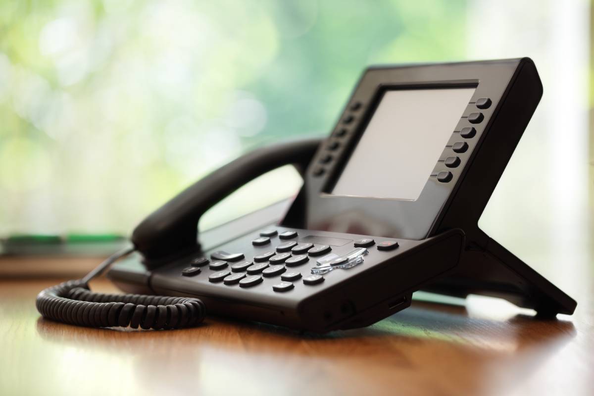 A black phone sitting on a brown desk