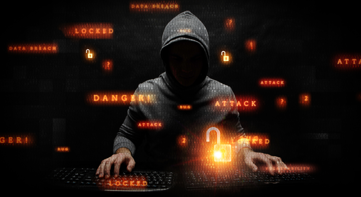A man in a hoodie standing while typing on two keyboards