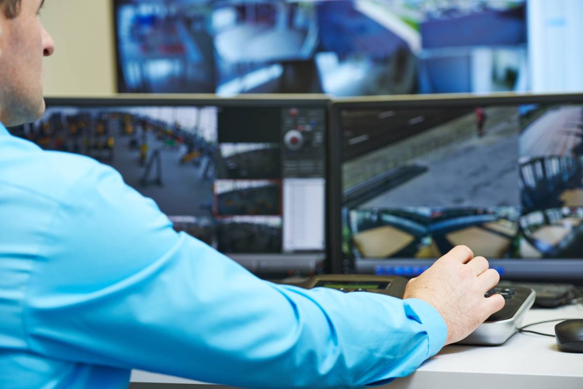 Employee reviewing security camera footage on three screens