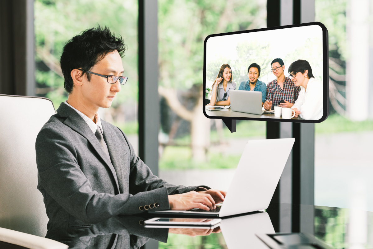 An Asian business man video conferencing with co-workers