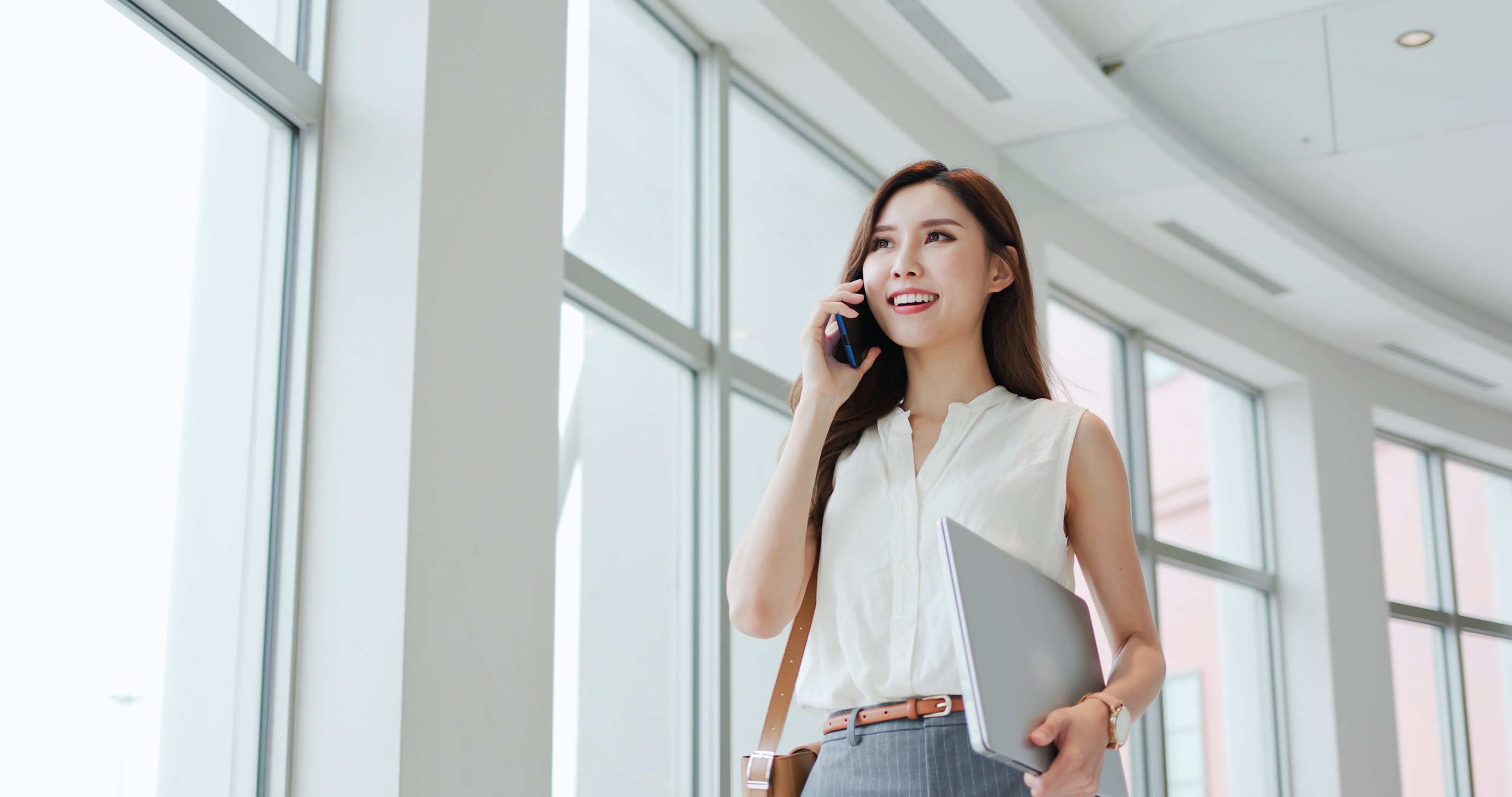 A women on her phone while walking through a large hall of an office building