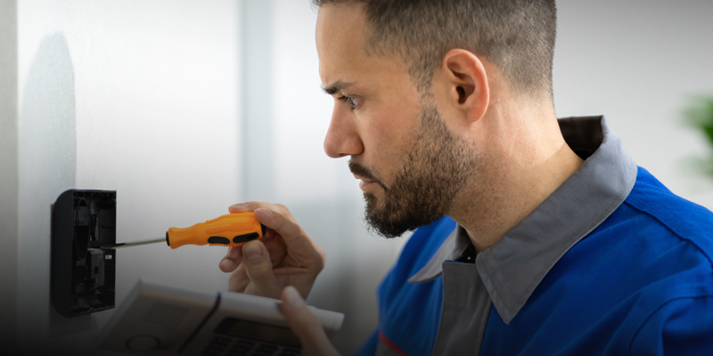 Installer mounting a card reader or electronic door lock in a commercial building.