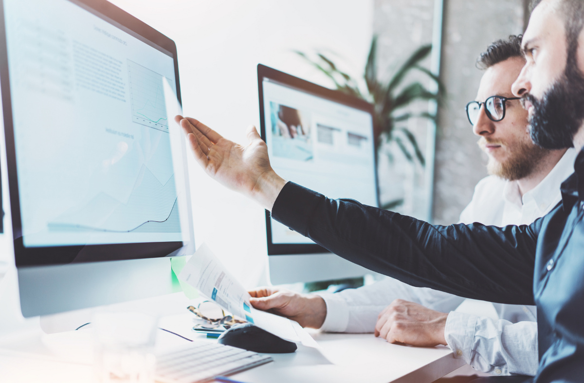 Two Businessmen Concentrating On and Gesturing at Computer Monitor