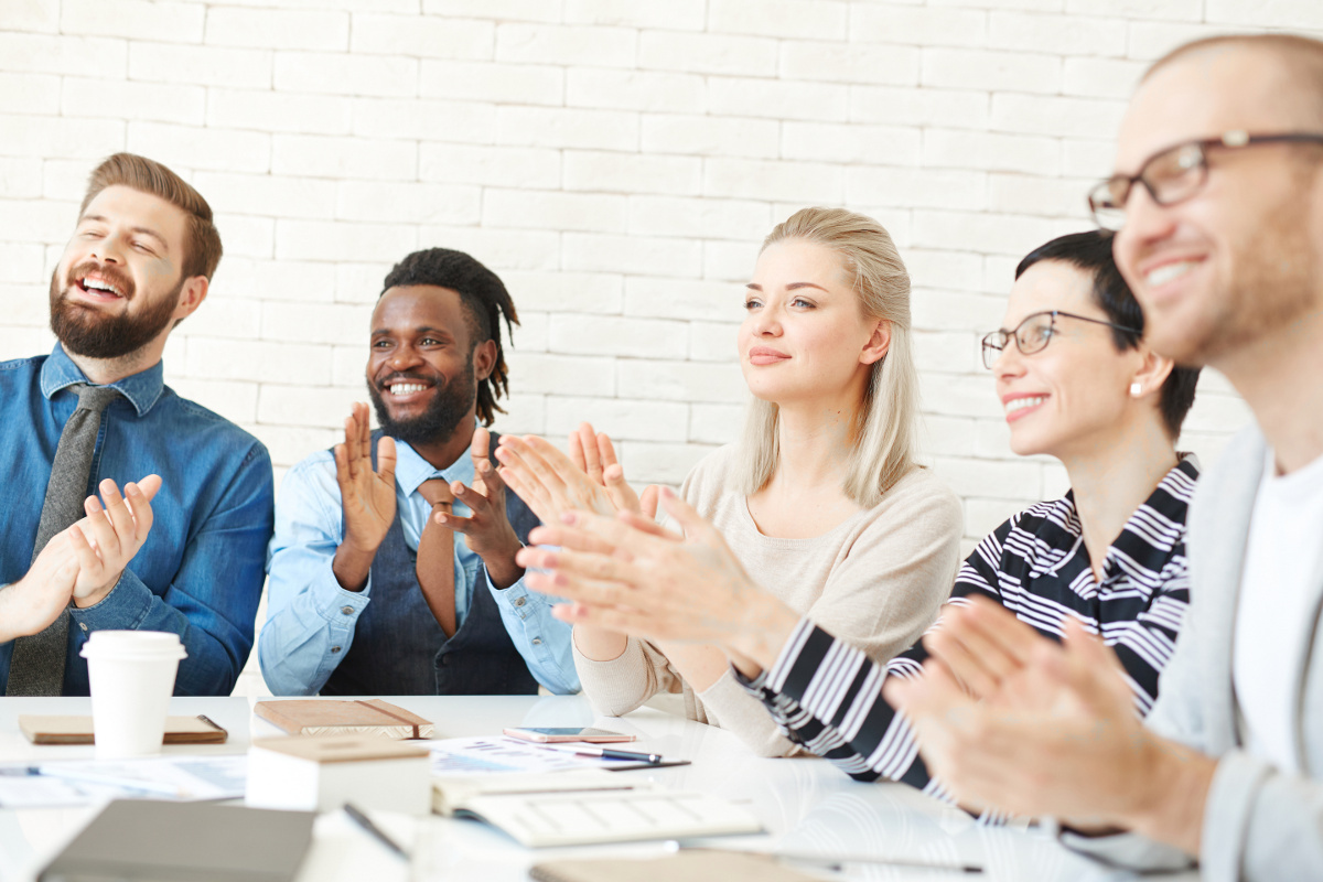 Group of Five Business People Seated Around Meeting Table Applauding