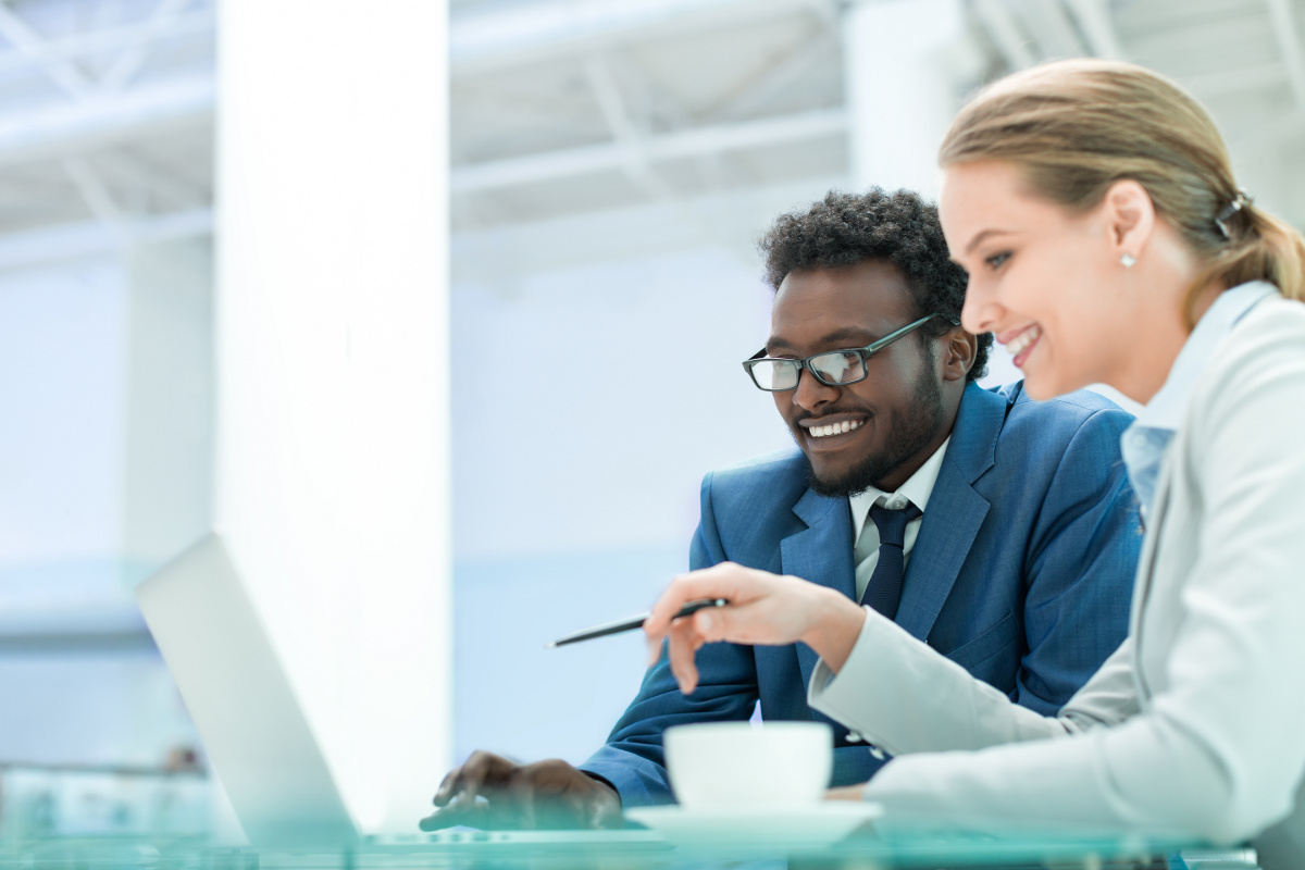 Male and Female Coworkers Smiling and Pointing at Laptop Computer