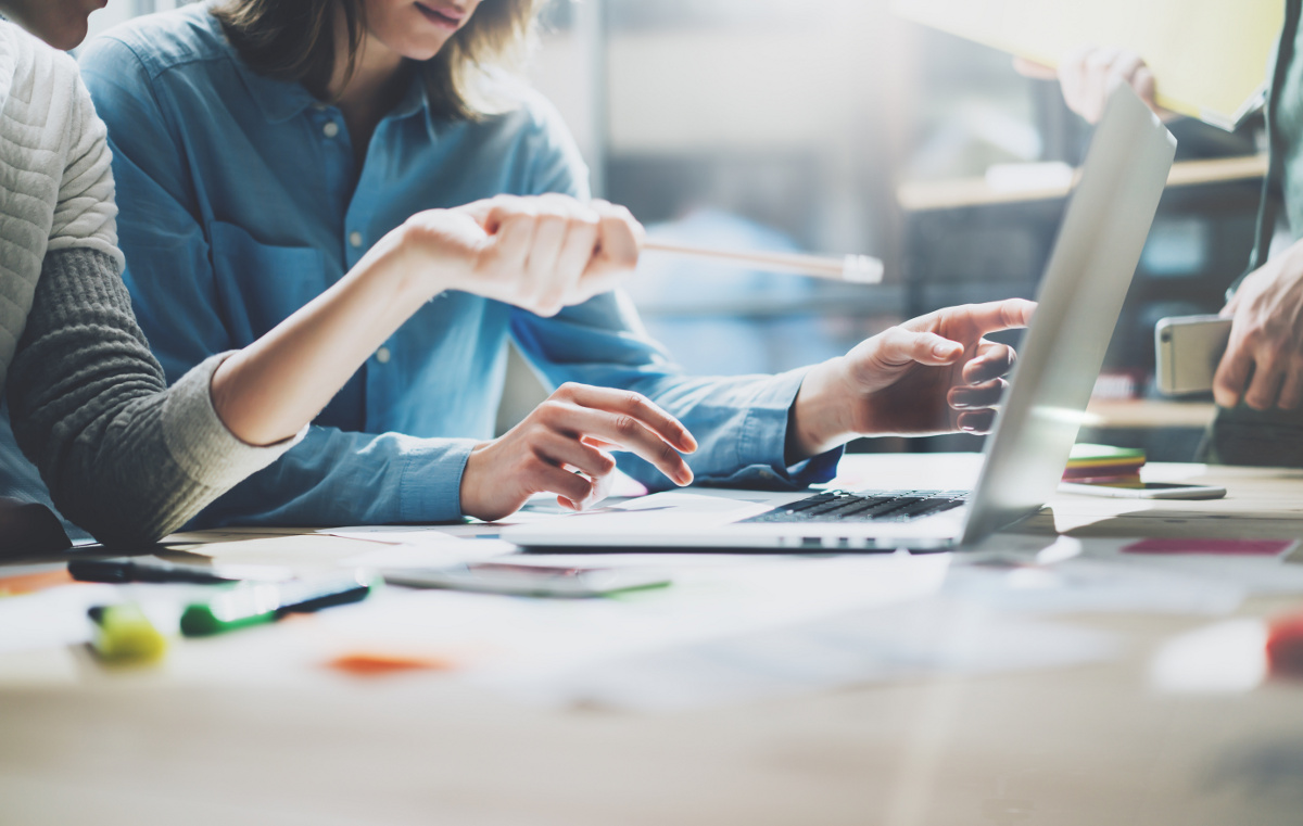 Close Up of Two Business People Gesturing Toward a Laptop Screen with a Pencil in Hand