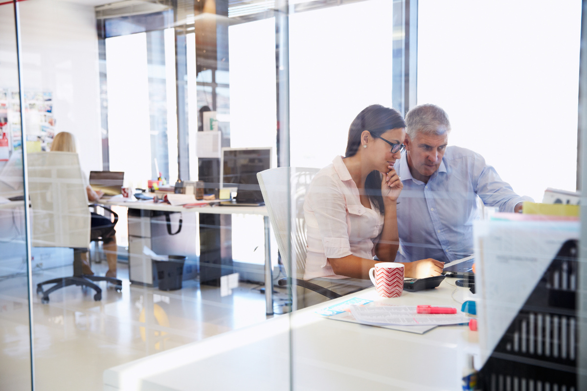 Male and Female Coworkers Looking Forward at Shared Desk Space