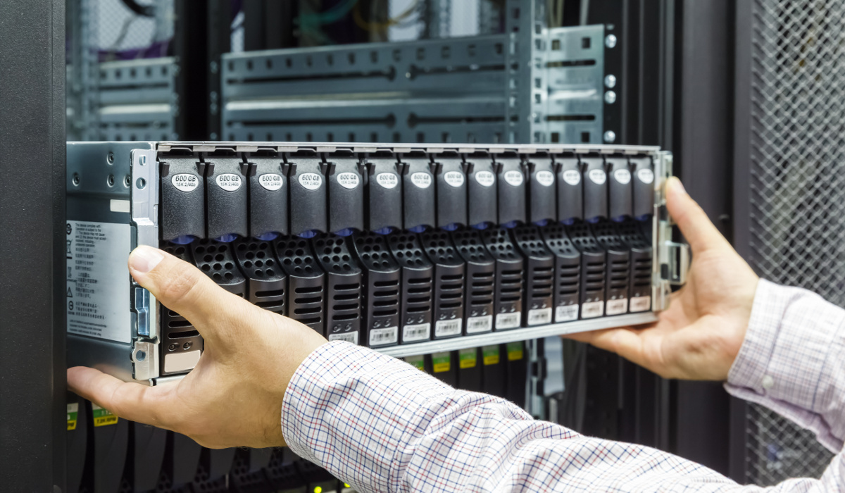 Hands sliding a storage server with rows of drive caddies into a rack