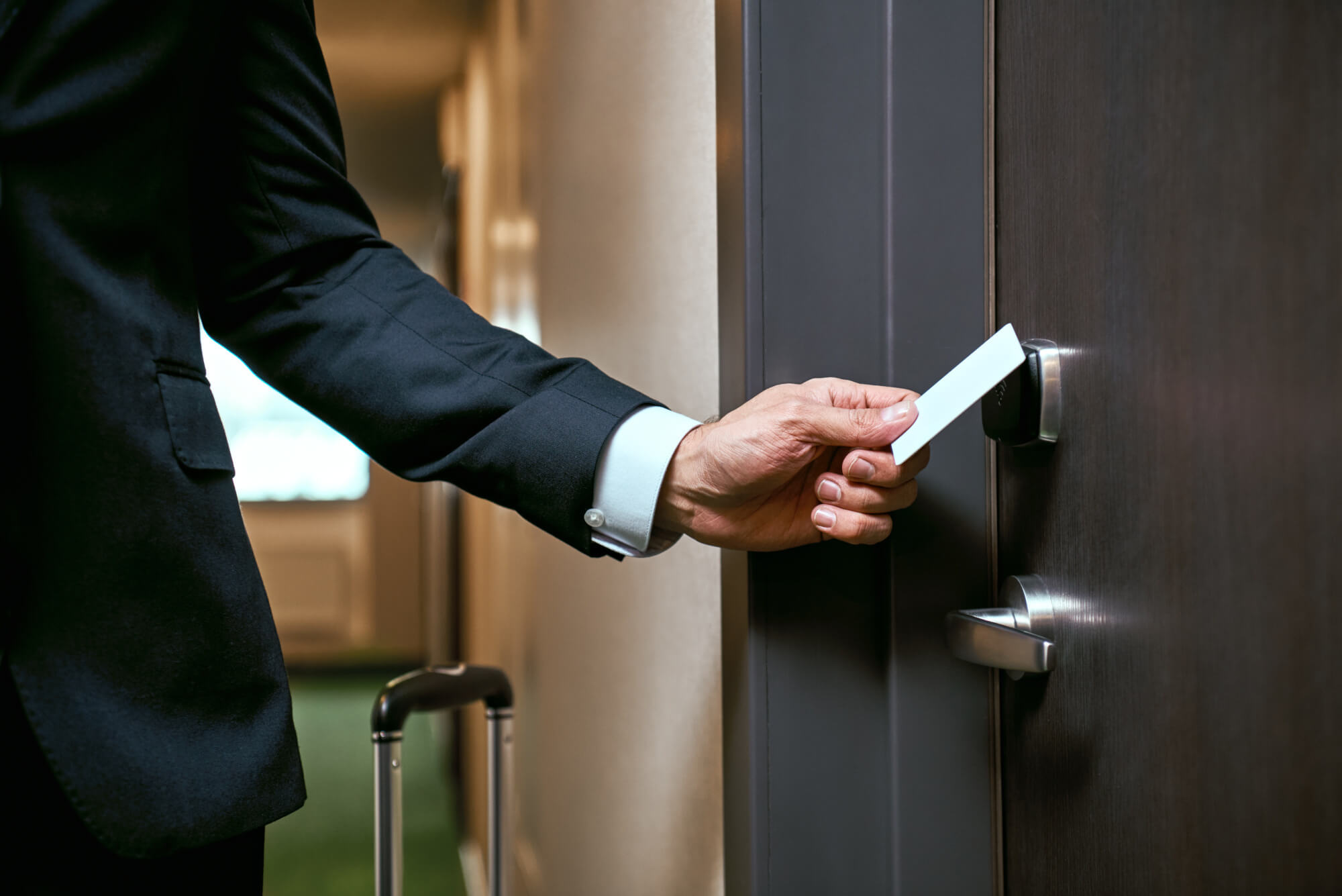 man in suit accessing a hotel room with a keycard