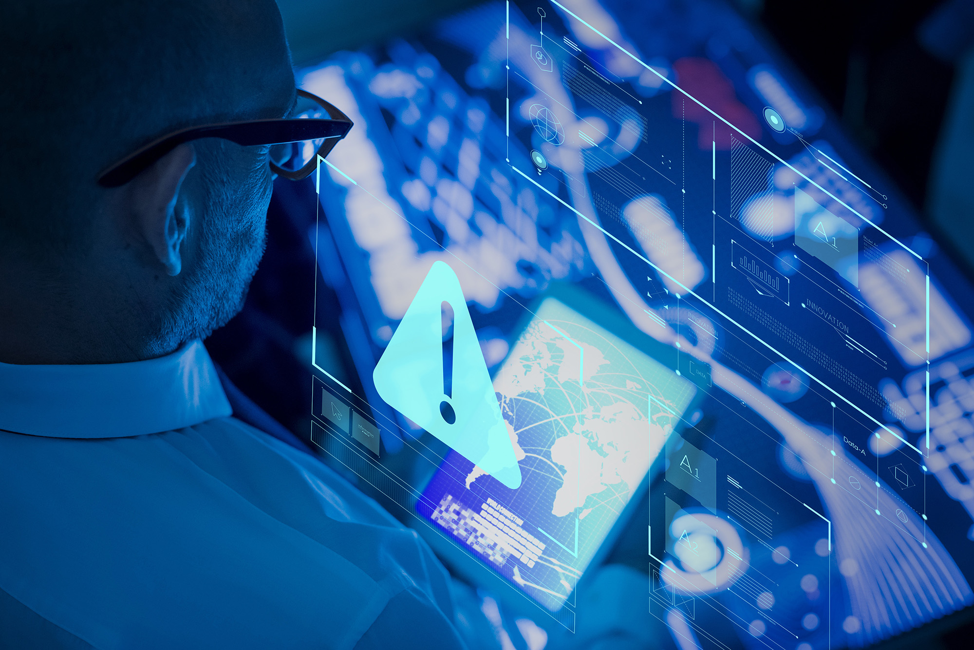 A man looking at a tablet while it projects a warning icon