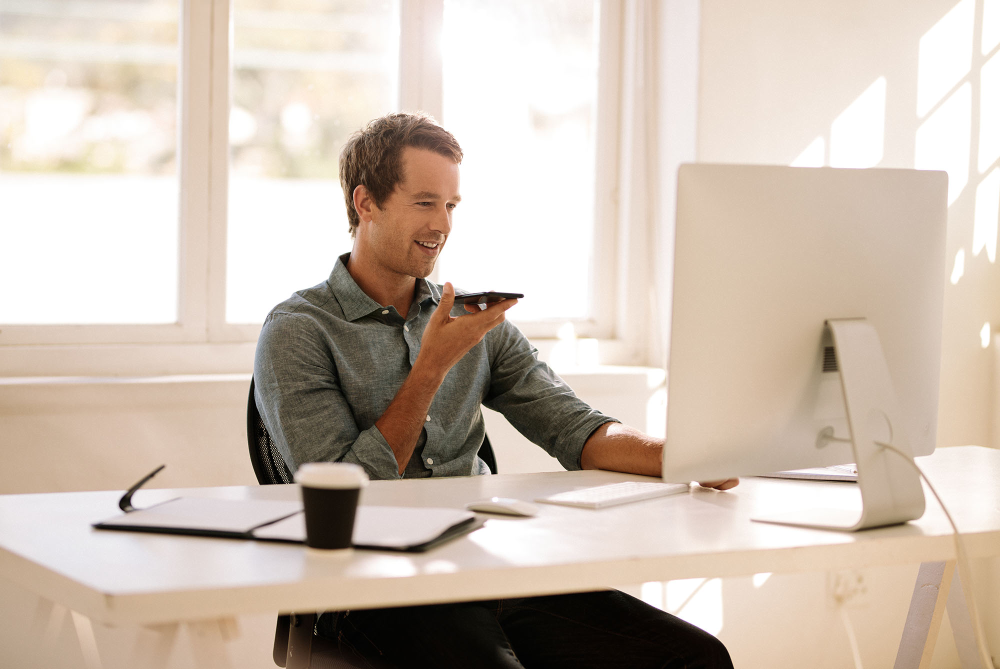 Male using laptop with mobile phone sitting on table next to it